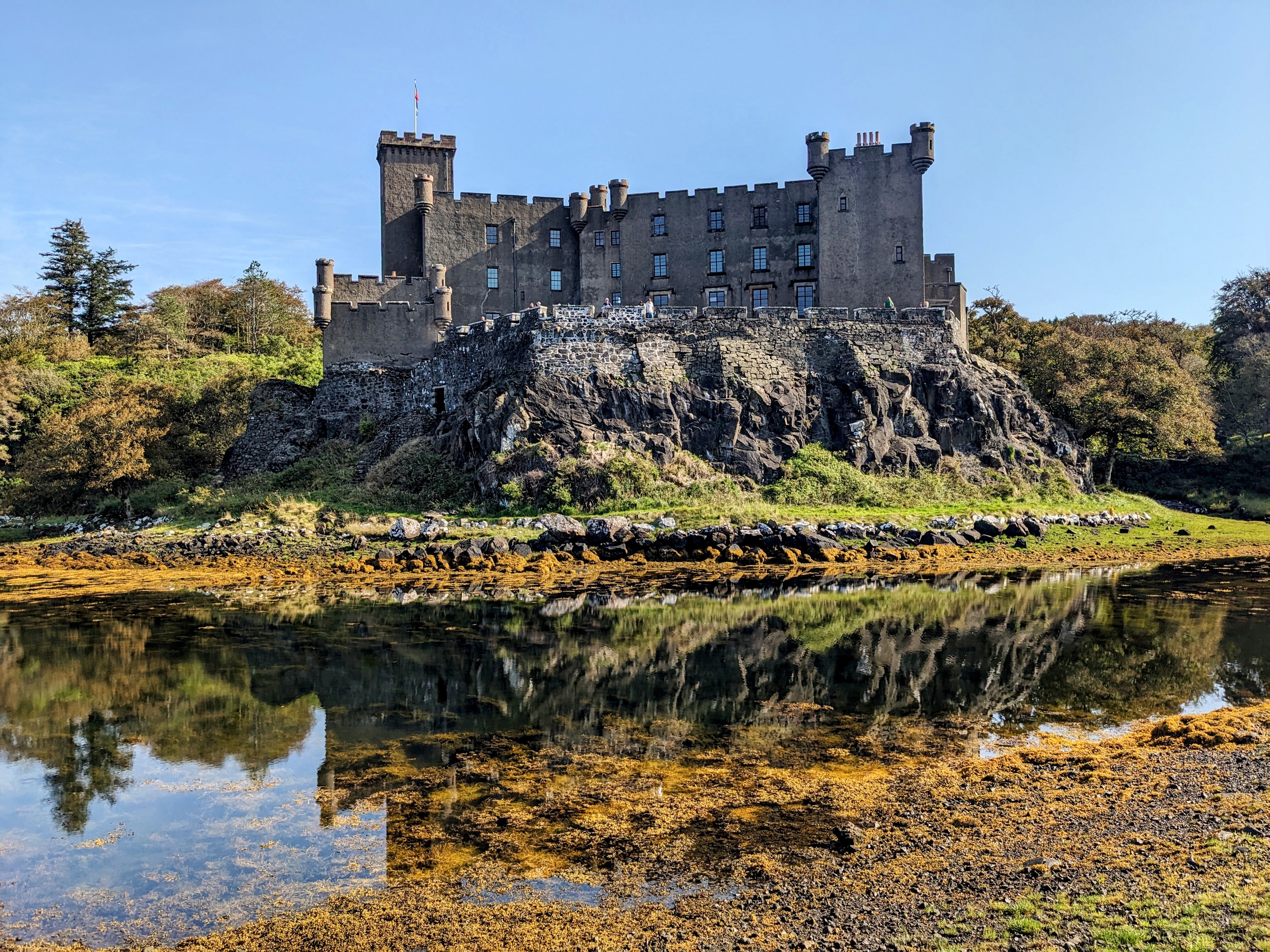 The Dunvegan Castle in Isle of Skye, Northern Scotland featuring beautiful natural scenery, a clear sky, rich vegetation, and a body of water